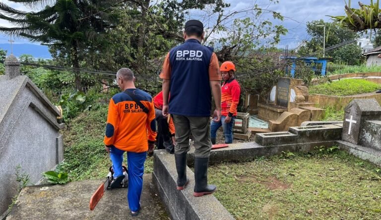Pohon kersen tumbang akibat angin kencang di kawasan Makam China Ngebong, Jalan Ahmad Dahlan, Sidorejo Lor, Kota Salatiga, Jumat (27/2/2026). BPBD Salatiga memastikan tidak ada korban jiwa. Pohon setinggi sekitar lima meter menimpa nisan makam dan kabel optik, lalu dievakuasi petugas menggunakan gergaji mesin.